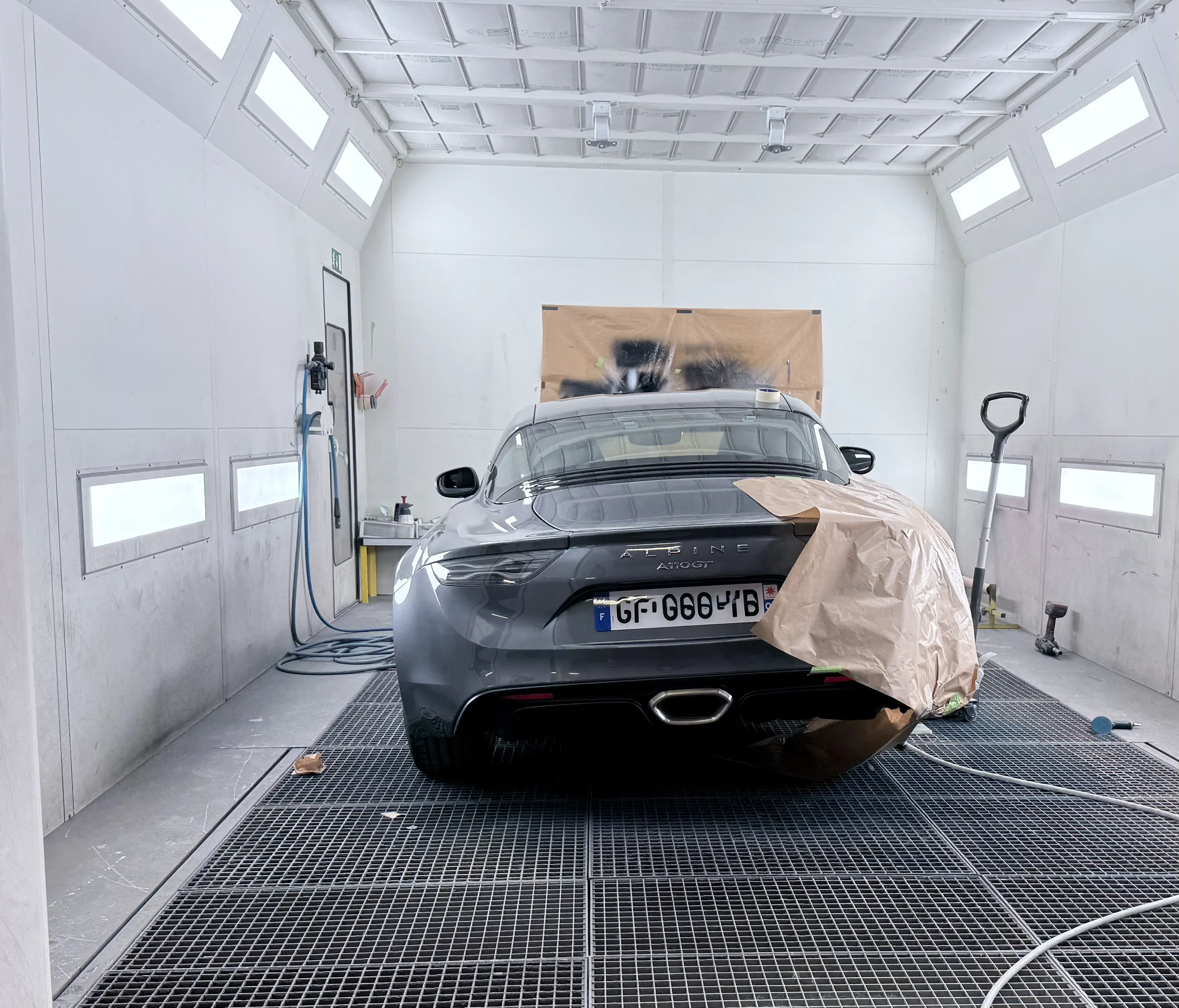 Alpine A110 GT grise en cabine de peinture chez AutoMania Atelier à Eysines, raccord de bas de caisse et rénovation de jantes près de Bordeaux en Gironde